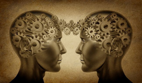 Business partnership and teamwork symbol represented by two human heads with gears connected together as a symbol of network referrals and relationships on an old grunge parchement background.